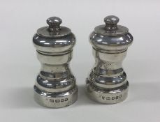 A pair of circular silver pepper grinders of shape