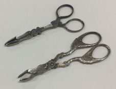 Two pairs of silver plated manicure tongs. Est. £2