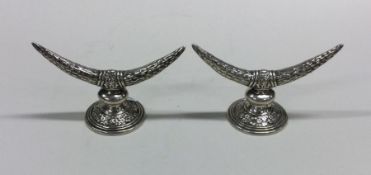 A pair of heavy cast silver knife rests in the for