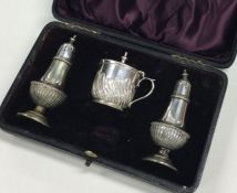 A cased silver plated three piece half fluted crue