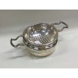 A pierced silver tea strainer on matching stand. A