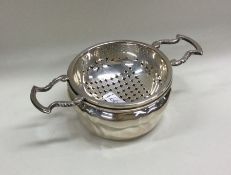 A pierced silver tea strainer on matching stand. A