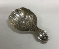 A chased silver caddy spoon decorated with flowers