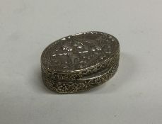 A stylish silver pill box decorated with figures.