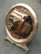 A large circular silver mirror on bracket feet wit