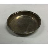 A small circular silver bottle coaster with reeded