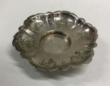 A Continental silver saucer decorated with flowers