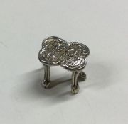 A small miniature silver table with embossed decor