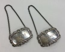 A pair of silver wine labels with floral decoratio