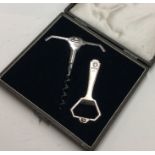 A stylish boxed silver corkscrew together with mat