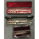 Two cased flutes together with a cased piccolo. Es
