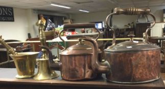 Two copper kettles together with a brass pestle an