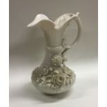 A Belleek pottery jug decorated with flowers in re