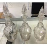 A group of three glass decanters with matching sto