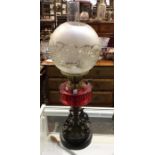 A good cranberry glass oil lamp with cast iron res