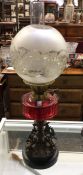 A good cranberry glass oil lamp with cast iron res