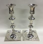 A pair of heavy cast silver square based candlesti