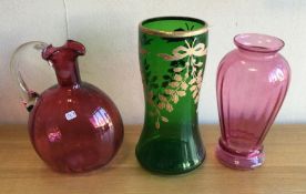 A cranberry glass vase together with other coloure