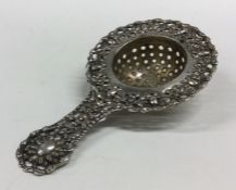 A pierced Continental silver tea strainer with emb