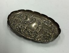 A chased silver pin dish decorated with scrolls an