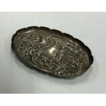 A chased silver pin dish decorated with scrolls an