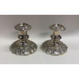 A heavy pair of embossed silver candlesticks with