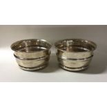 A pair of Edwardian silver wine coasters with maho