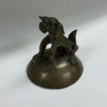 A Chinese brass figure of a seated dog on domed pe
