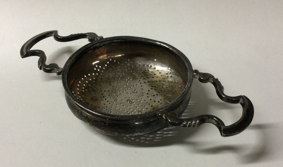 A George II silver tea strainer with reeded border