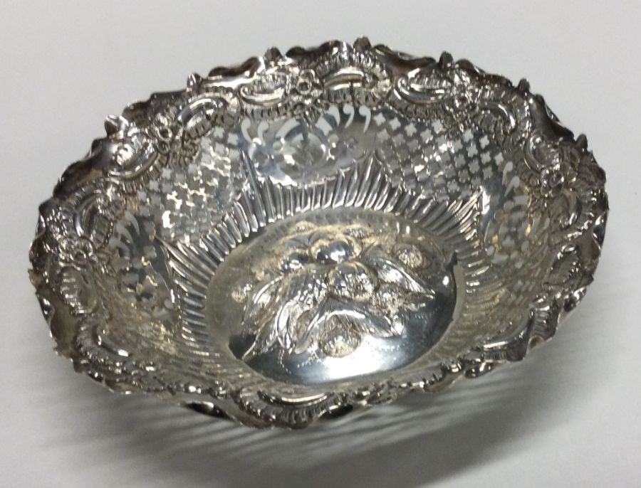 A circular chased silver dish with scroll decorati