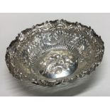 A circular chased silver dish with scroll decorati
