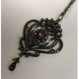 A large ruby and diamond drop pendant with scroll