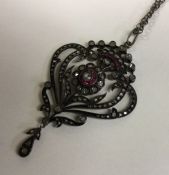 A large ruby and diamond drop pendant with scroll