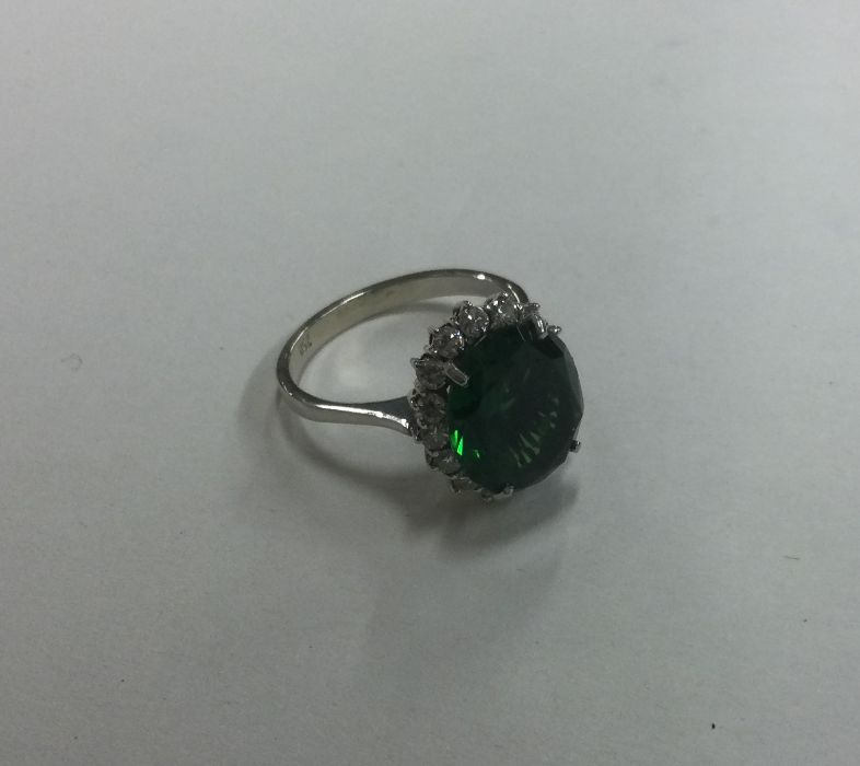 An attractive oval green stone and diamond cluster