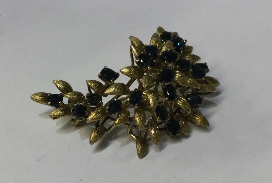 A 14 carat gold sapphire brooch of stylised form.