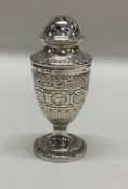 A Victorian silver pepper with chased decoration.