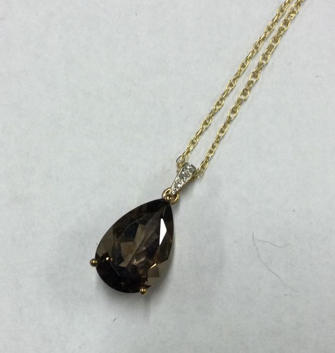 A diamond mounted topaz pendant on fine link chain