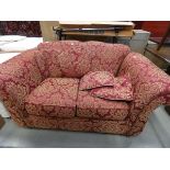 A maroon and gold floarl 2 seater sofa