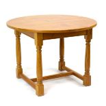 A late 20th century golden oak centre table, the circular surface on four turned supports,