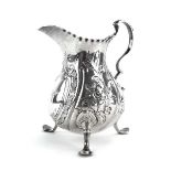 A George III silver cream jug of typical ovoid form with leaf capped c-scroll handle on three