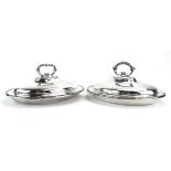 A pair of silver plated covered entree dishes of oval form,