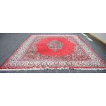 A Persian woolen carpet, the bright red ground with a central floral medallion and matching bands,