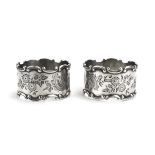 A pair of Edwardian silver napkin rings with c-scroll border and foliate engraving, maker WHS,