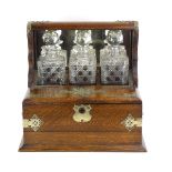 A Victorian oak three-bottle tantalus with silver-plated mounts,