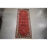 (4) Small runner carpet with red ground and cream border, approx. 180cm x 70cm