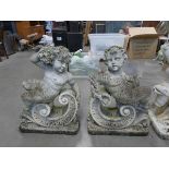 2 reconstituted stone putti with bearing wheatsheafs and flowers on scroll