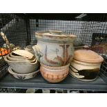 A cage containing a quantity of green and brown glazed casserole dishes