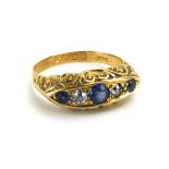 An early 20th century 18ct yellow gold ring set three graduated sapphires and two diamonds in a