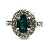 A 14ct white gold ring set oval cut emerald within a border of small diamonds,