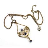 An Edwardian 9ct yellow gold openwork pendant set sapphires and seed pearls on a later plated chain